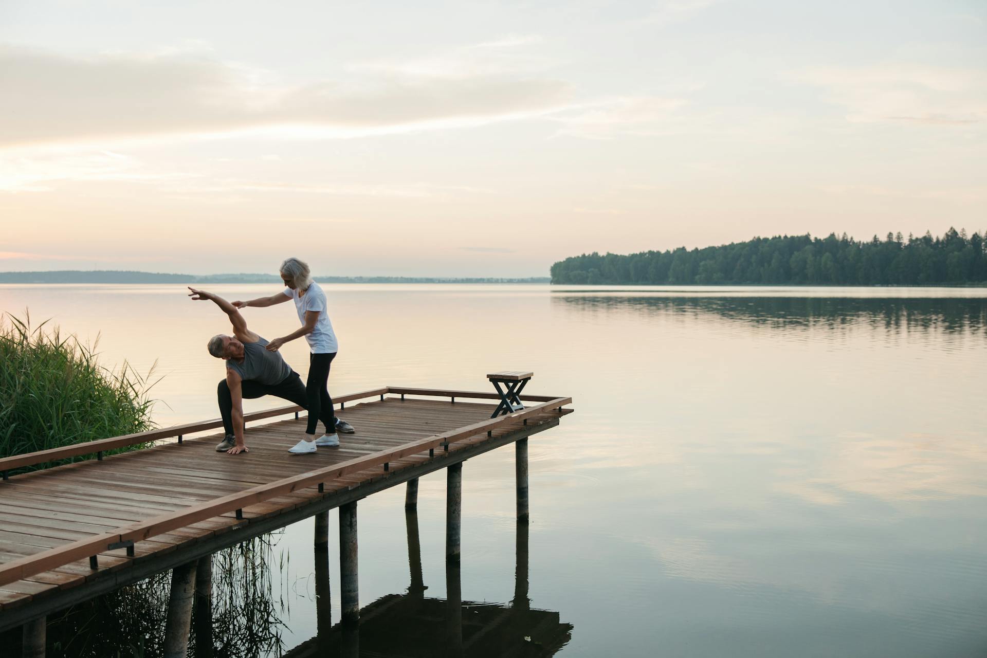 Yogadocente doet een yogapositie bij een man op een steiger 