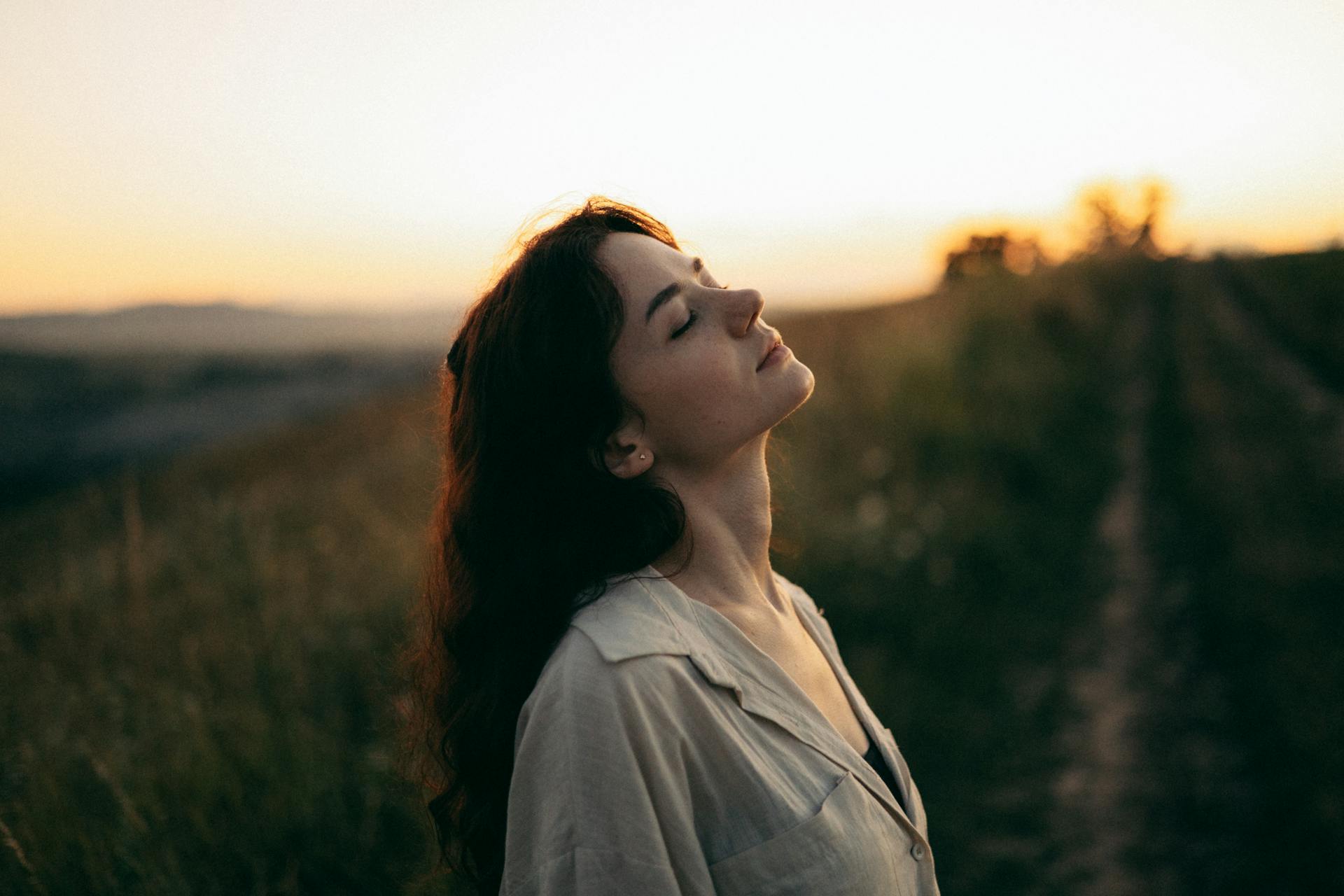 Foto van het zij profiel van een vrouw bij een wijngaarde met zonsondergang