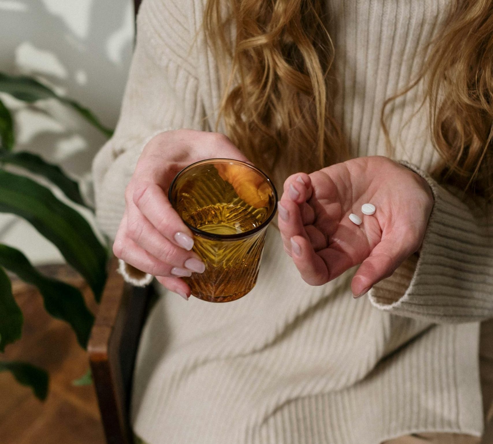 Handen met in een hand allergiepillen en in de andere hand een glas water